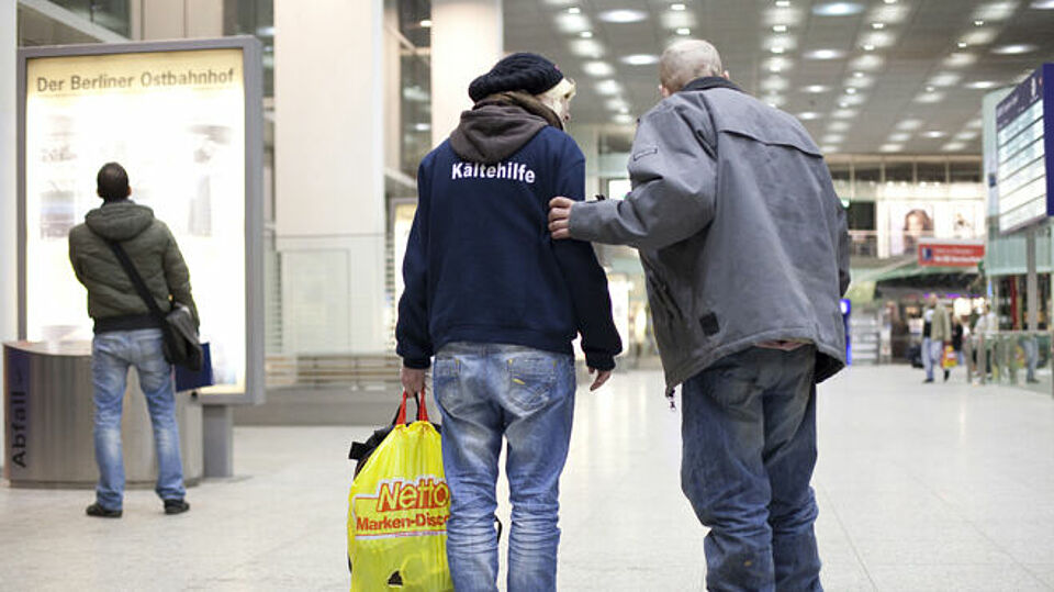 2 Männer von hinten fotografiert die sich unter die Arme greifen
